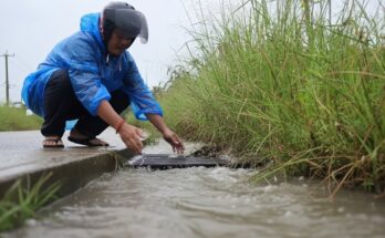 Culvert drain blocked with debris being unclogged using DIY methods, shovel, and water flushing