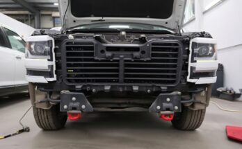 Mechanic demonstrating step-by-step removal of a 2014–2018 Chevy Silverado front bumper using basic tools, showing bolts, clips, brackets, and safe disconnection methods for DIY truck repair.
